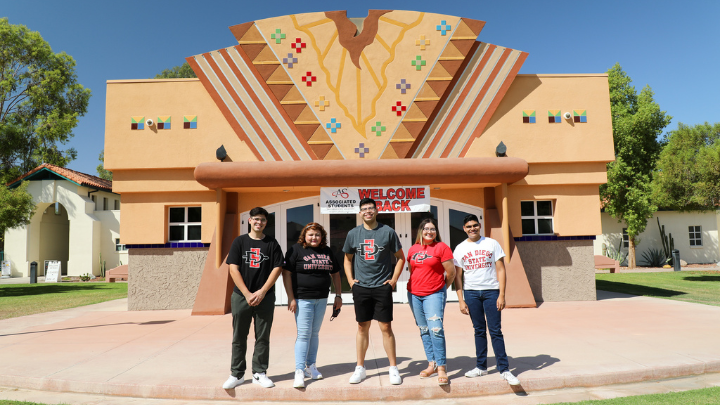 five people standing in front of a building