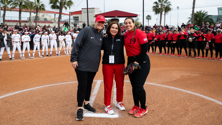 3 women smiling in front of a softball team